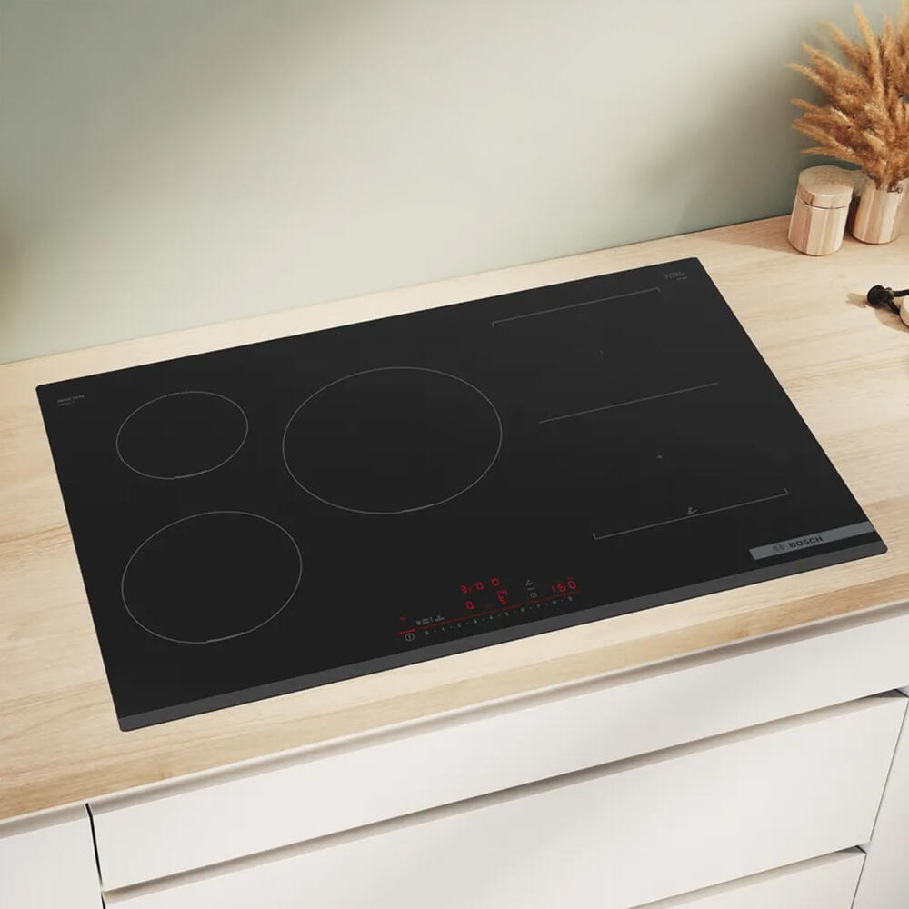 Inductiekookplaat met een strak design tegen een vage groene achtergrond.