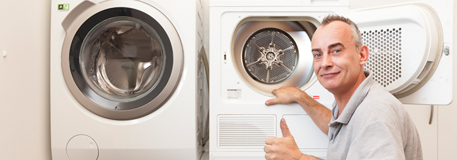 Man voor een wasmachine en droger, duimen omhoog.