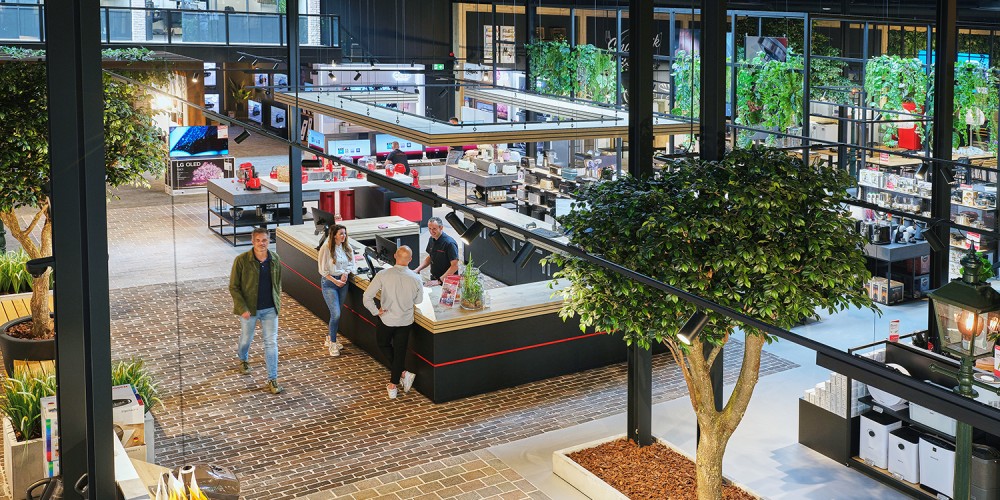 Een moderne winkel met een open indeling, groenvoorzieningen en klanten die aan een balie staan.