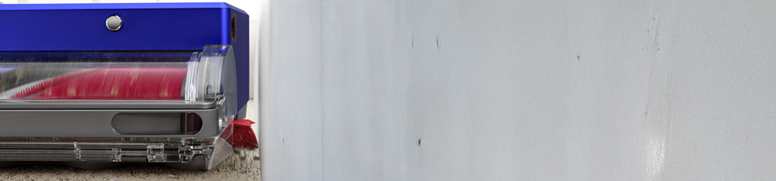 Een blauwe robotstofzuiger met rode borstels tegen een witte muur.