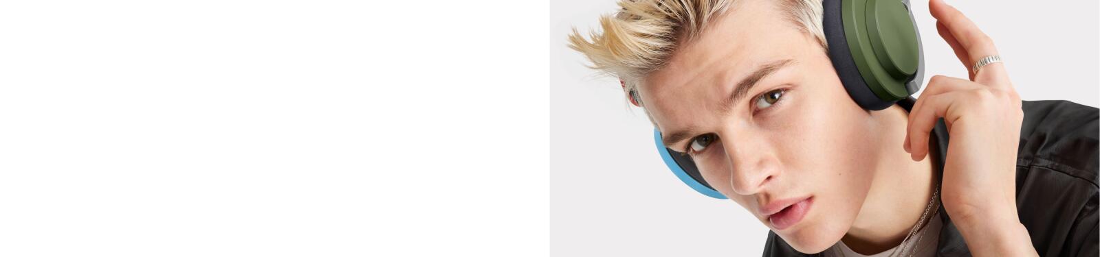 Een persoon draagt groene koptelefoon en kijkt in de camera.