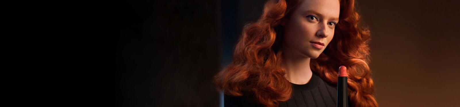 Een persoon met rood haar houdt een stylingsapparaat vast.