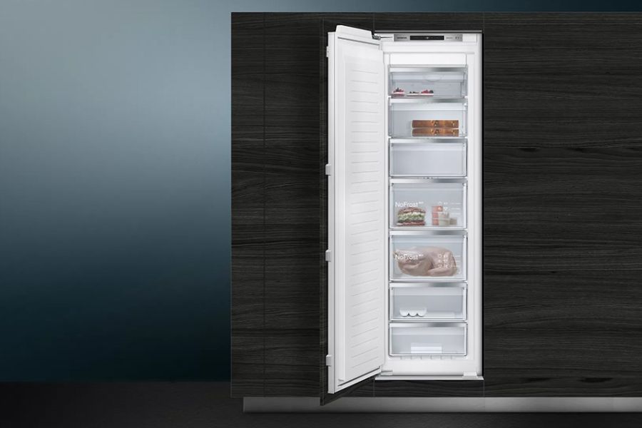 Ingebouwde zwarte vriezer in een keuken, met de deur geopend om planken en ingevroren producten te tonen.