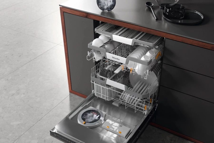 Ingebouwde vaatwasser met uitgeschoven rekken vol borden, kopjes en bestek.