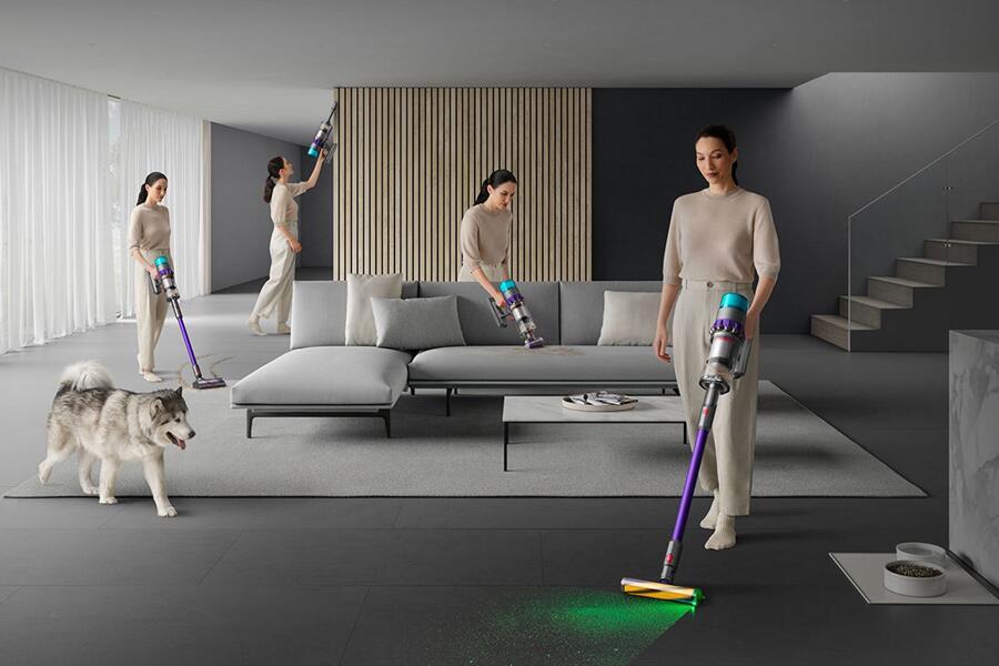 Een vrouw stofzuigt in een moderne woonkamer met een hond in de buurt.