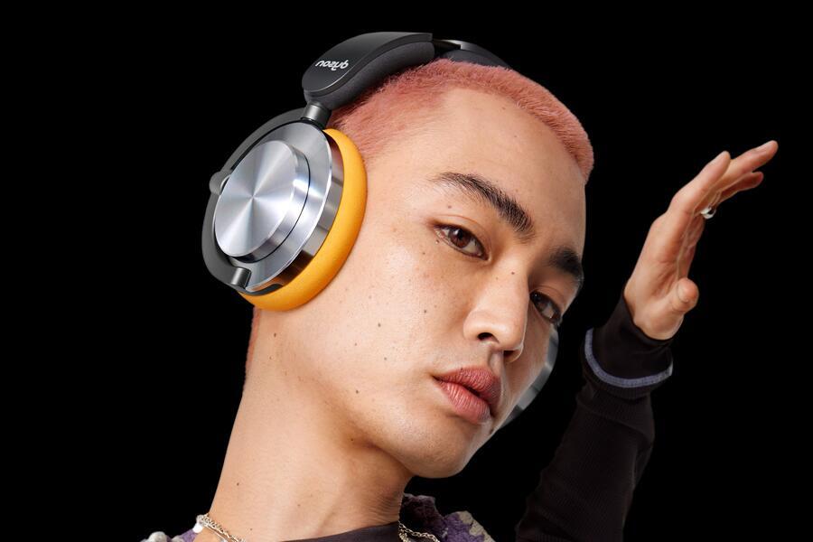 Persoon met roze haar draagt grote koptelefoon, zwarte achtergrond.